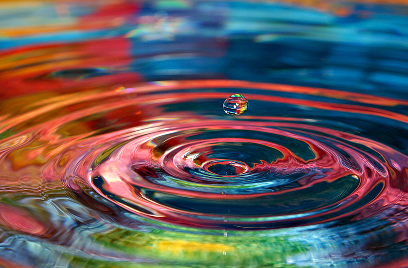 A water droplet creating a ripple with neon colors added.