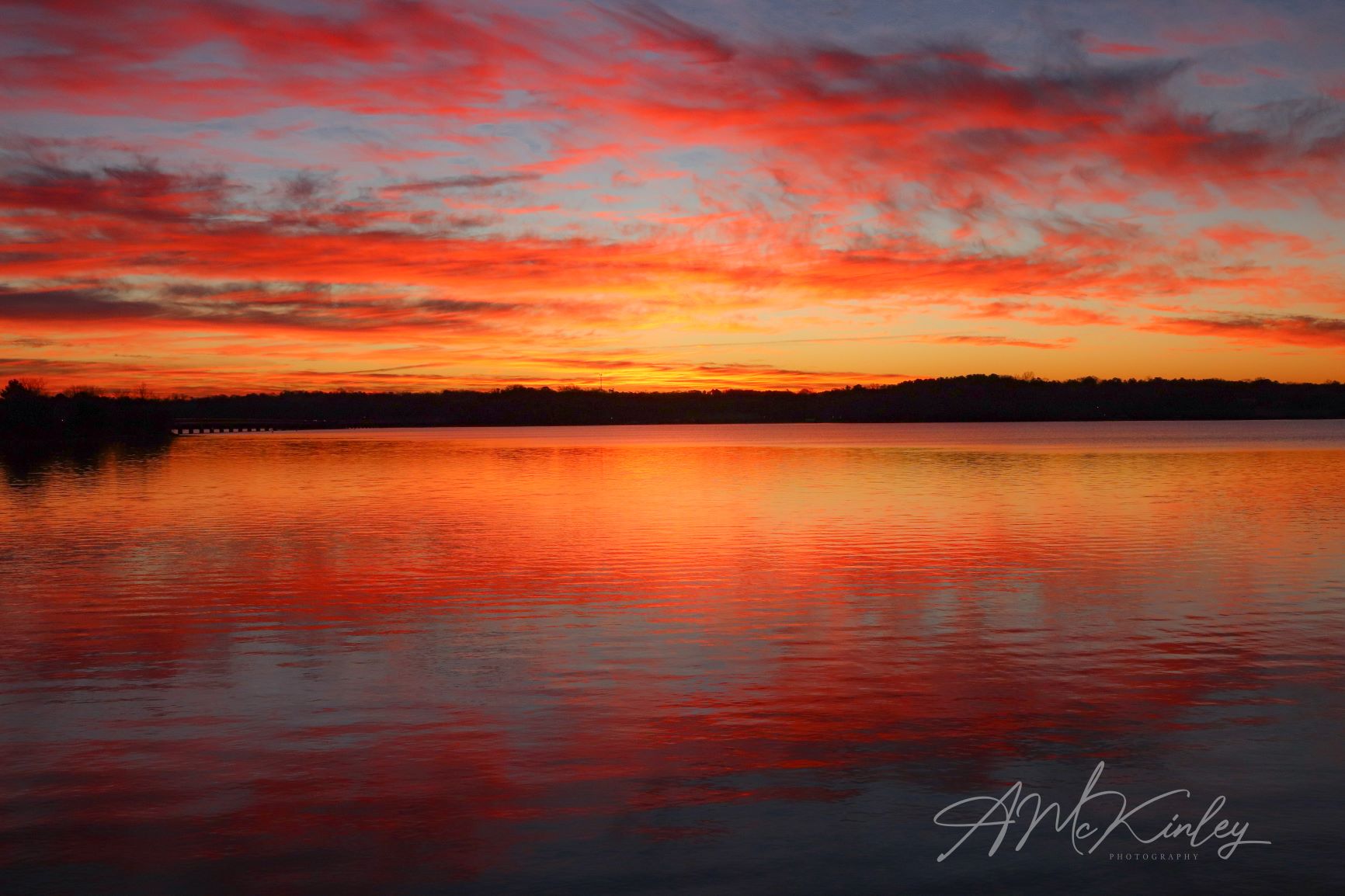 Sunrise over a lake with vivid orange, red, and yellow colors. Photo courtesy of A.McKinley photography