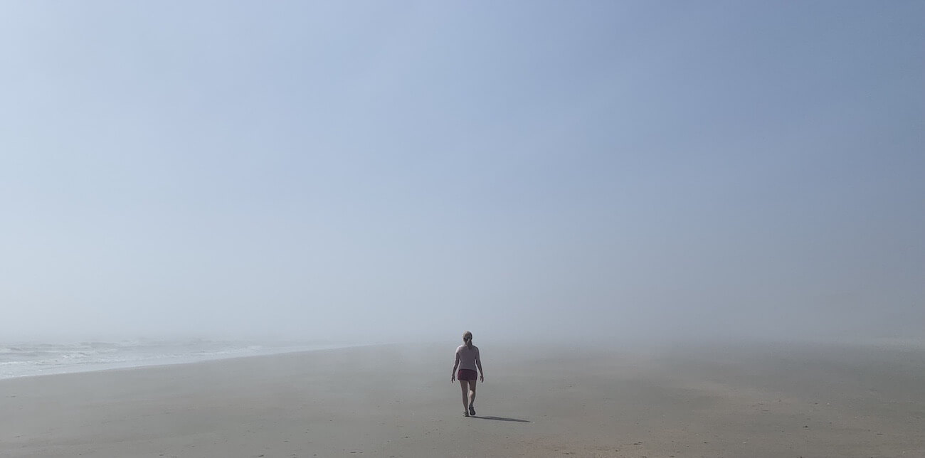 A woman walking into a fogged landscape.