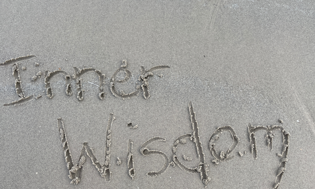 The words Inner Wisdom written in wet sand